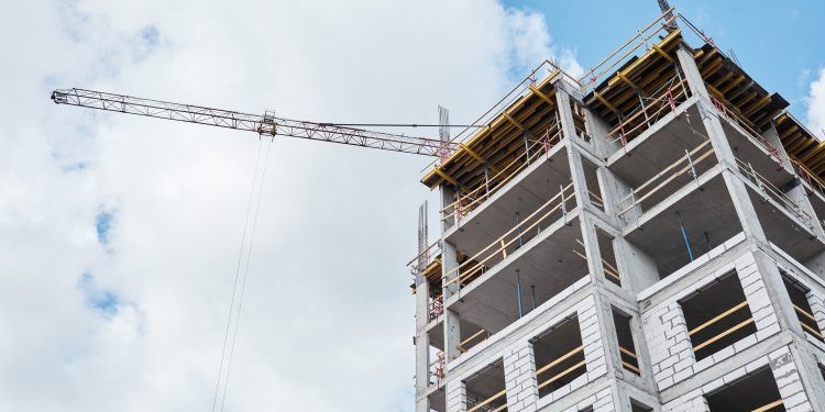 Low angle shot of residential building under construction with brick and concrete structure against blue sky, copy space